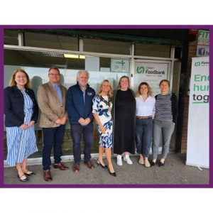 Group Outside Lisburn Foodbank: Seven adults stand outside Lisburn Foodbank, to mark the official opening of the new reception, with a banner reading “End hunger together.”